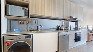 A modern kitchen with a built-in washer-dryer, microwave, and oven. - Sentinel Luxury Suites (Cape Town)