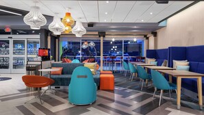 A modern lounge area with seating arrangements, pendant lighting, and large windows offering a view of the outside. - TRU BY Hilton Round Rock (Round Rock)