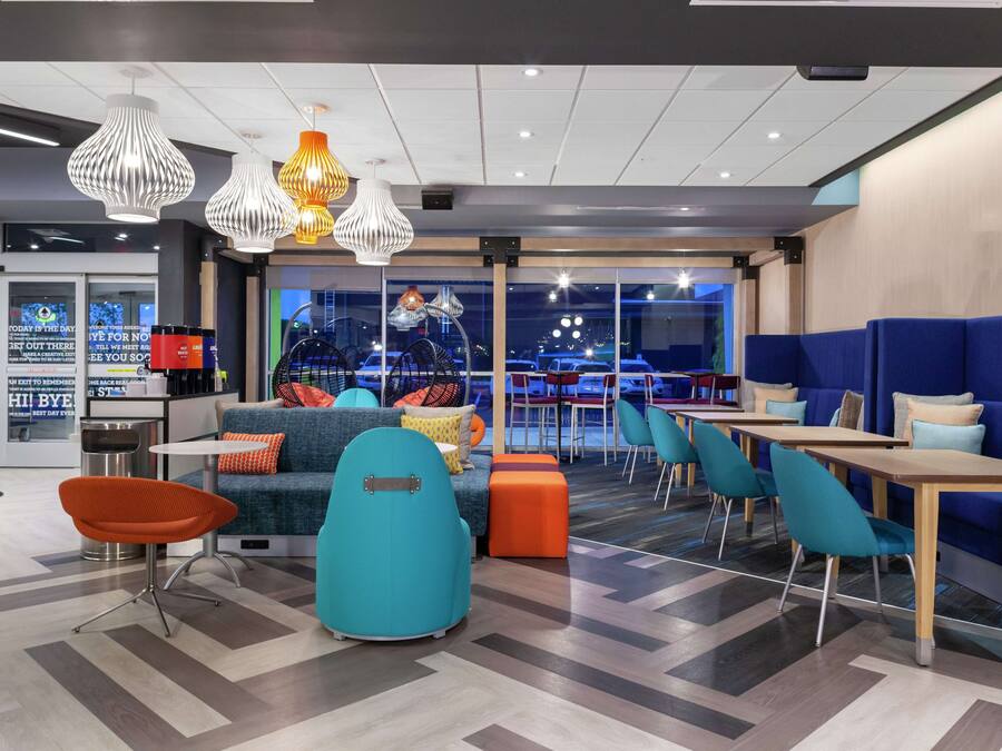 A modern lounge area with seating arrangements, pendant lighting, and large windows offering a view of the outside.