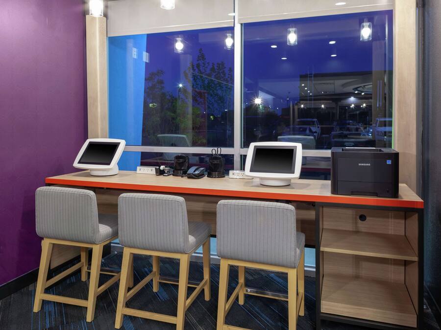 Un espace de travail équipé de deux écrans, d’une imprimante et de trois chaises.
