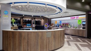 A hotel reception area with a wooden reception desk, a digital display, and a breakfast counter. - TRU BY Hilton Round Rock (Round Rock)