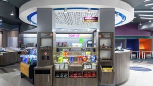 A 24/7 market area with a breakfast section, vending machines, and a checkout counter. - TRU BY Hilton Round Rock (Round Rock)