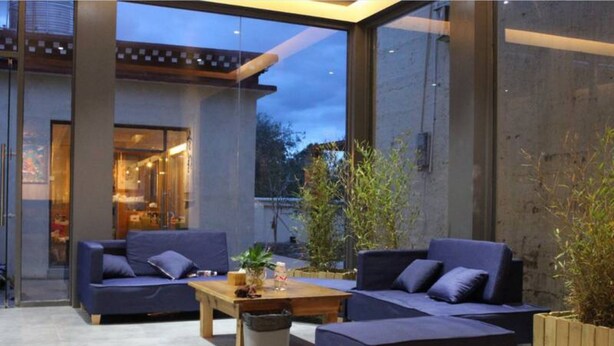 A modern outdoor seating area with two sofas and a coffee table, surrounded by large windows and potted plants. - Shangri-La Youyou Inn (Deqin)