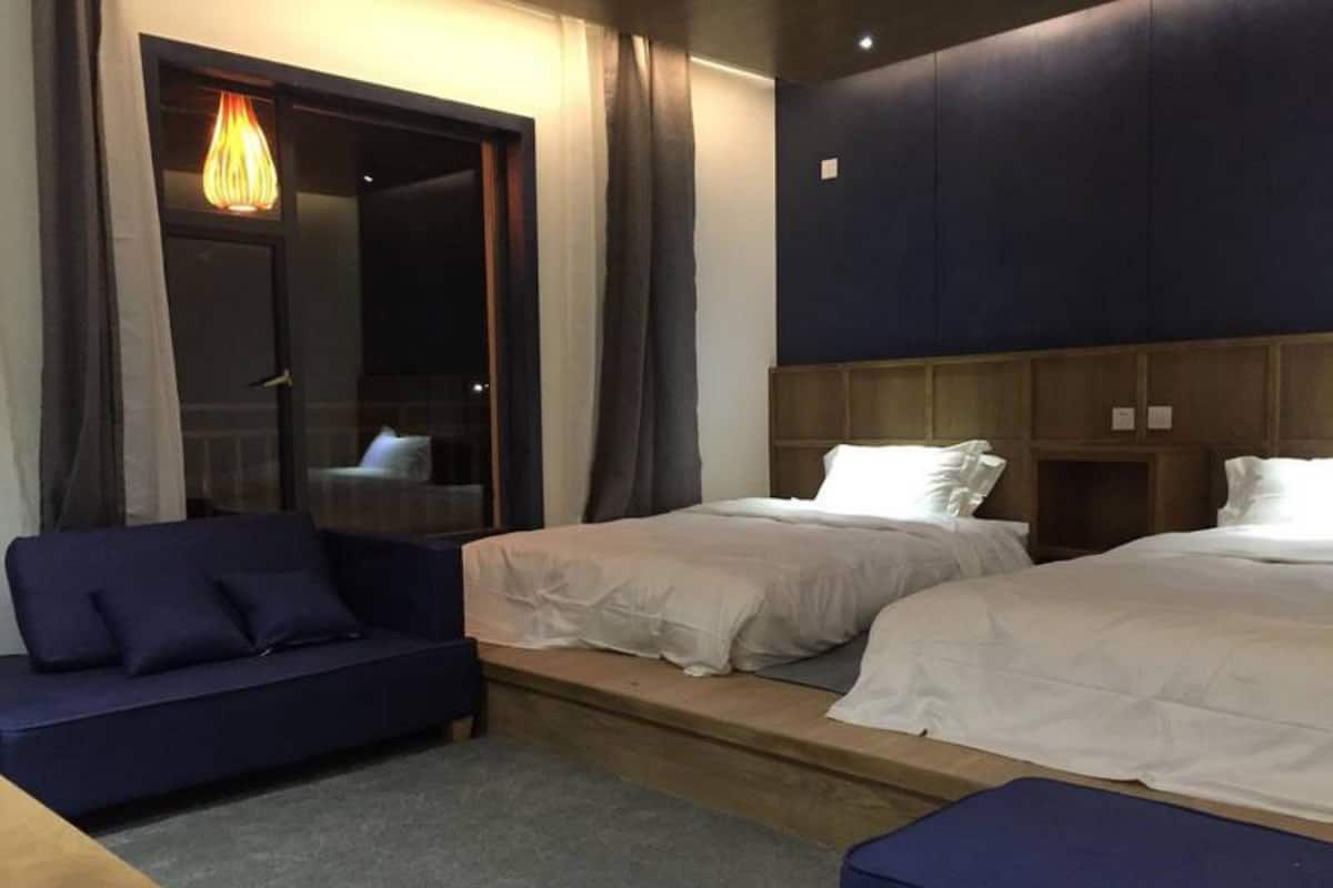 A hotel room with two beds, a sofa, and a wooden table.