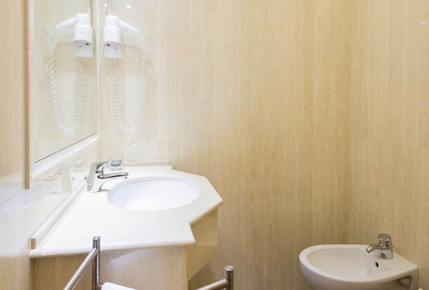 Un baño moderno con un lavamanos grande, un bidé y un espejo.