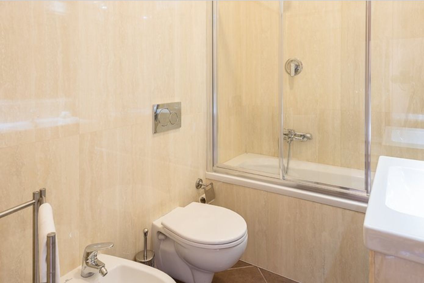 Un baño con inodoro, bidé y ducha con mampara de vidrio.