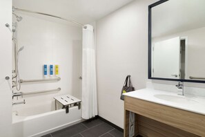 A modern bathroom with a bathtub, shower, and vanity.