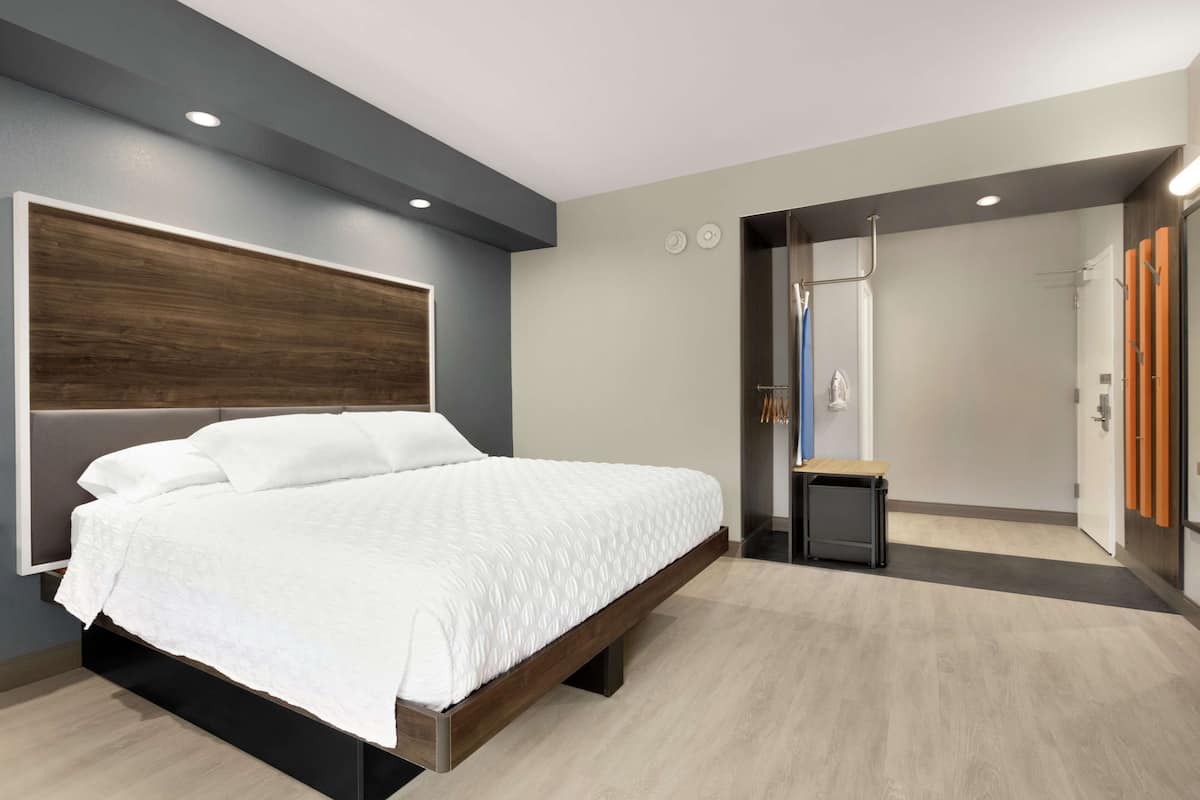 Une chambre à coucher moderne avec un grand lit, une petite table de chevet et un dressing.