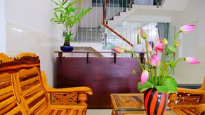 A wooden reception desk with a potted plant and a vase of flowers. - The Art - Big Sea Villa Hoi An Riverside (Da Nang)