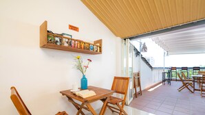 A wooden table with chairs, a bookshelf with books, and a vase with flowers. - The Art - Big Sea Villa Hoi An Riverside (Da Nang)
