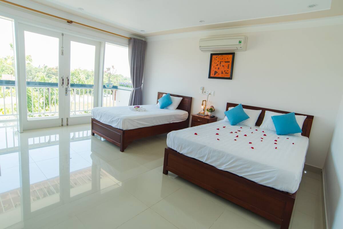A hotel room with two beds, a balcony, and an air conditioning unit.