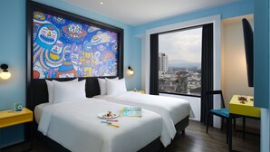 A hotel room with two beds, a large window with a city view, a colorful abstract painting on the wall, and a small table with a toy. - de Braga, ARTOTEL Curated (Bandung)