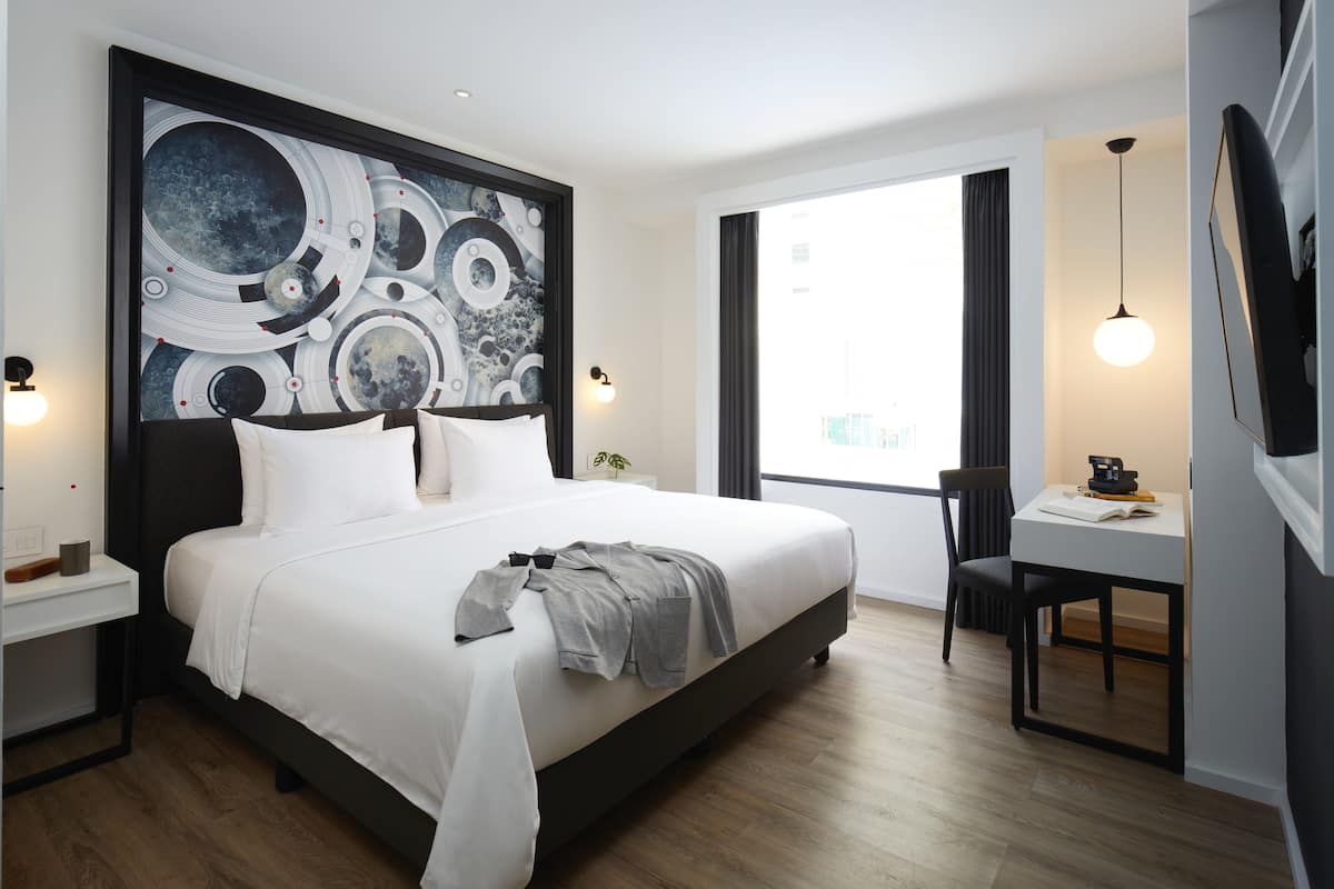 Habitación de hotel moderna con una cama grande, un escritorio y un cuadro abstracto de gran tamaño en la pared.