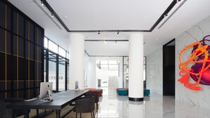 A modern office space with a long table, chairs, and two Apple iMac computers. - de Braga, ARTOTEL Curated (Bandung)