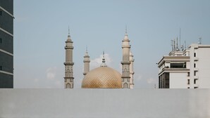 A swimming pool with a mosque in the background. - de Braga, ARTOTEL Curated (Bandung)