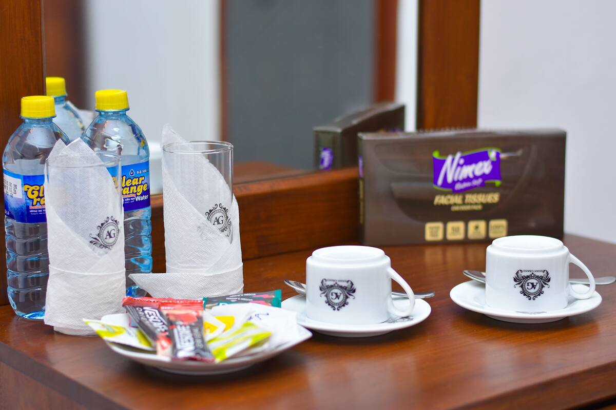 A hotel room table with water bottles, tissues, a facial tissue box, and cups with a logo.