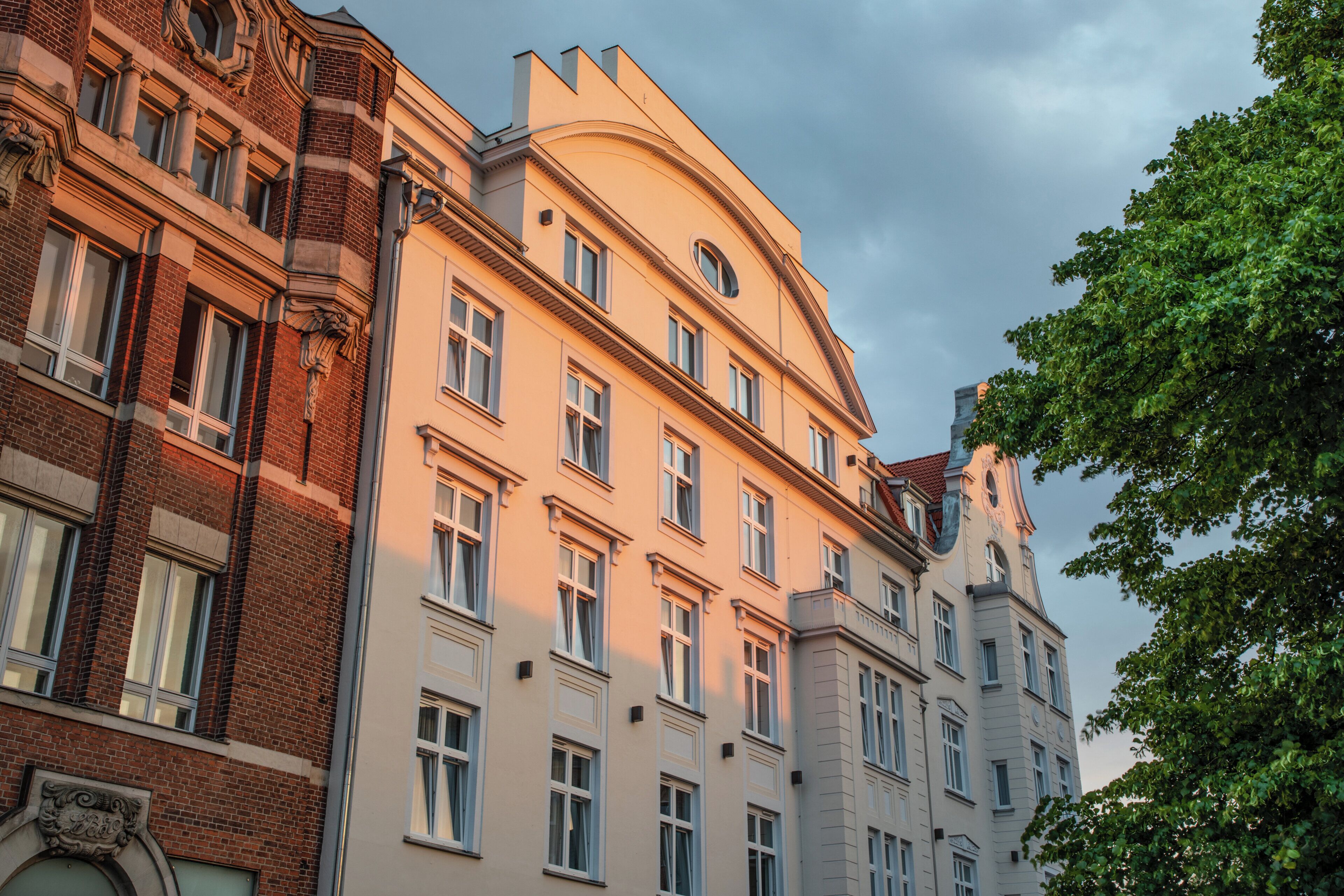 A multi-story building with a classic architectural style, featuring a mix of brick and plaster facades, large windows, and decorative elements.