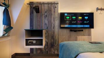 Une chambre d’hôtel moderne dotée d’un téléviseur fixé au mur qui permet de contrôler les différentes fonctions de la chambre, d’un mini-réfrigérateur intégré et d’un mur décoratif en bois.
