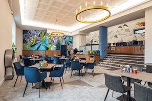 Un moderno vestíbulo de hotel con área de bar, asientos y una escalera que lleva al piso superior.