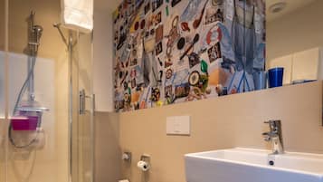 Un baño con ducha, inodoro, lavamanos y una pared decorada con diversos objetos.