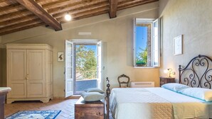 Un dormitorio con cama, armario, mesita de noche y ventana con vistas a zonas verdes.