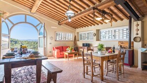 Un comedor espacioso con una mesa y sillas de madera, un sofá rojo y vistas al exterior.