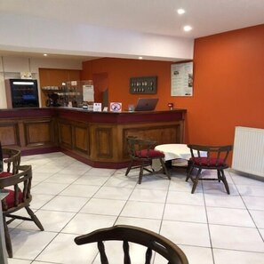 Un restaurante con mostrador, sillas de madera y una mesa blanca.