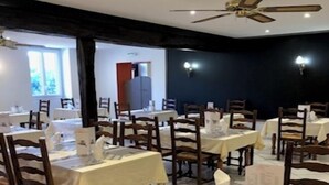 Een restaurant met meerdere tafels en stoelen, plafondventilatoren en wandlampen.
