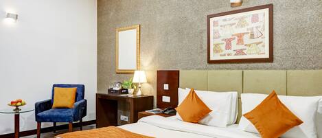 A hotel room with a bed, a chair, a desk, a lamp, and a framed picture on the wall.