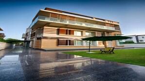 A modern multi-story residential building with a flat roof, large windows, and a balcony. - Stately Suites Golf Course Road (Gurugram)