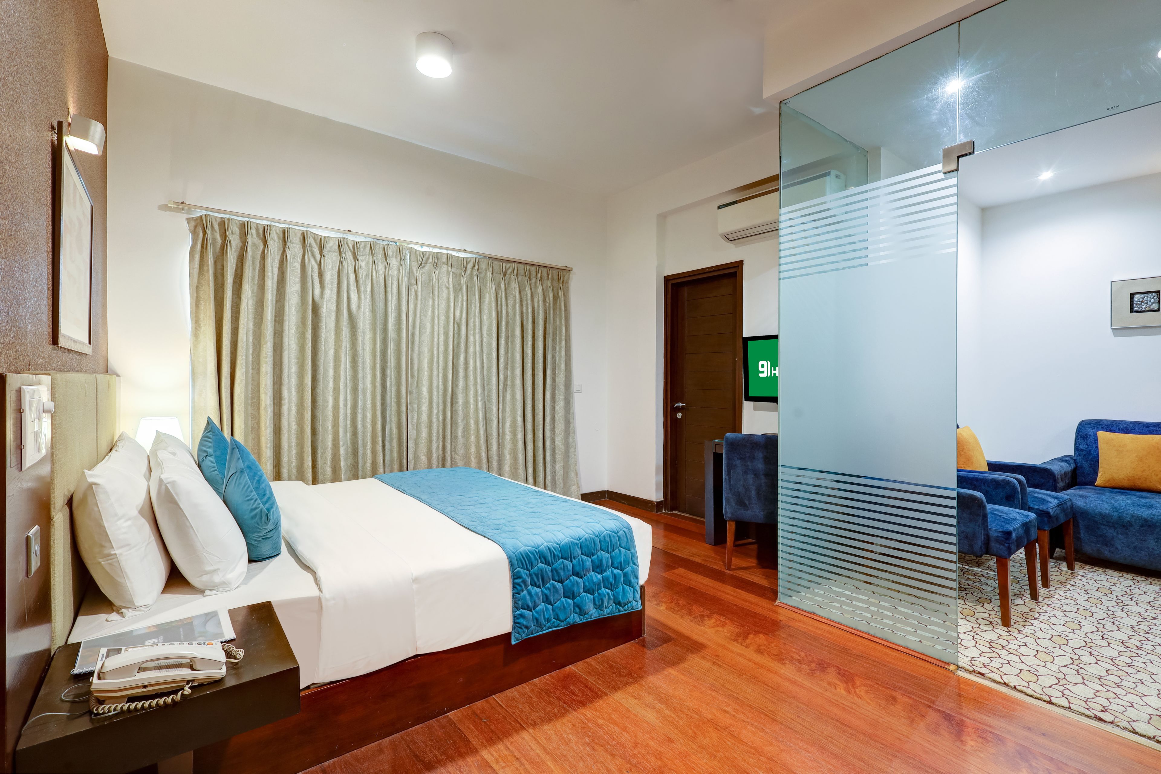 Une chambre d’hôtel comprenant un lit, un bureau avec un téléphone, une télévision et un coin salon avec des canapés.