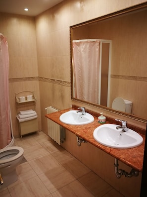 A bathroom with two sinks, a toilet, a shower curtain, and a large mirror. - Pension Areeta (Getxo)