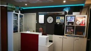 Un espace d’accueil comprenant un comptoir, des étagères, une horloge et un panneau indiquant la bienvenue aux visiteurs.