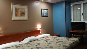 Une chambre d’hôtel avec un lit, un bureau doté d’une télévision et deux œuvres d’art encadrées accrochées au mur.