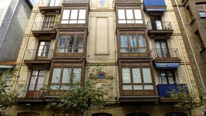 Un immeuble à plusieurs étages doté d’une entrée centrale, de balcons et d’une devanture visible.