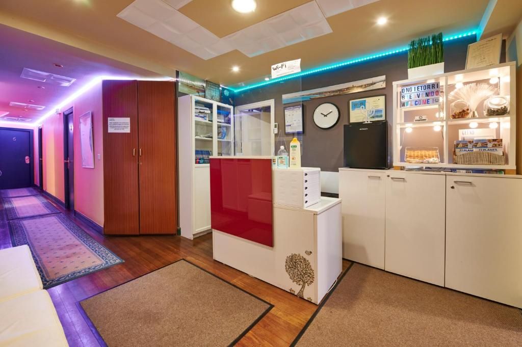 Un área de recepción con un reloj, un letrero de Wi-Fi y una exhibición de libros y revistas.