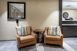 Two armchairs with striped pillows, a small round table, a clock, and a phone on a counter. - Candlewood Suites Rochester Mayo Clinic Area by IHG (Rochester)