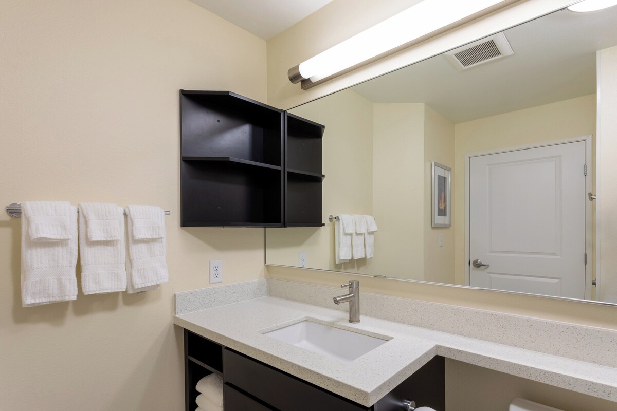 A bathroom with a white sink, a mirror, and two towel racks with white towels.