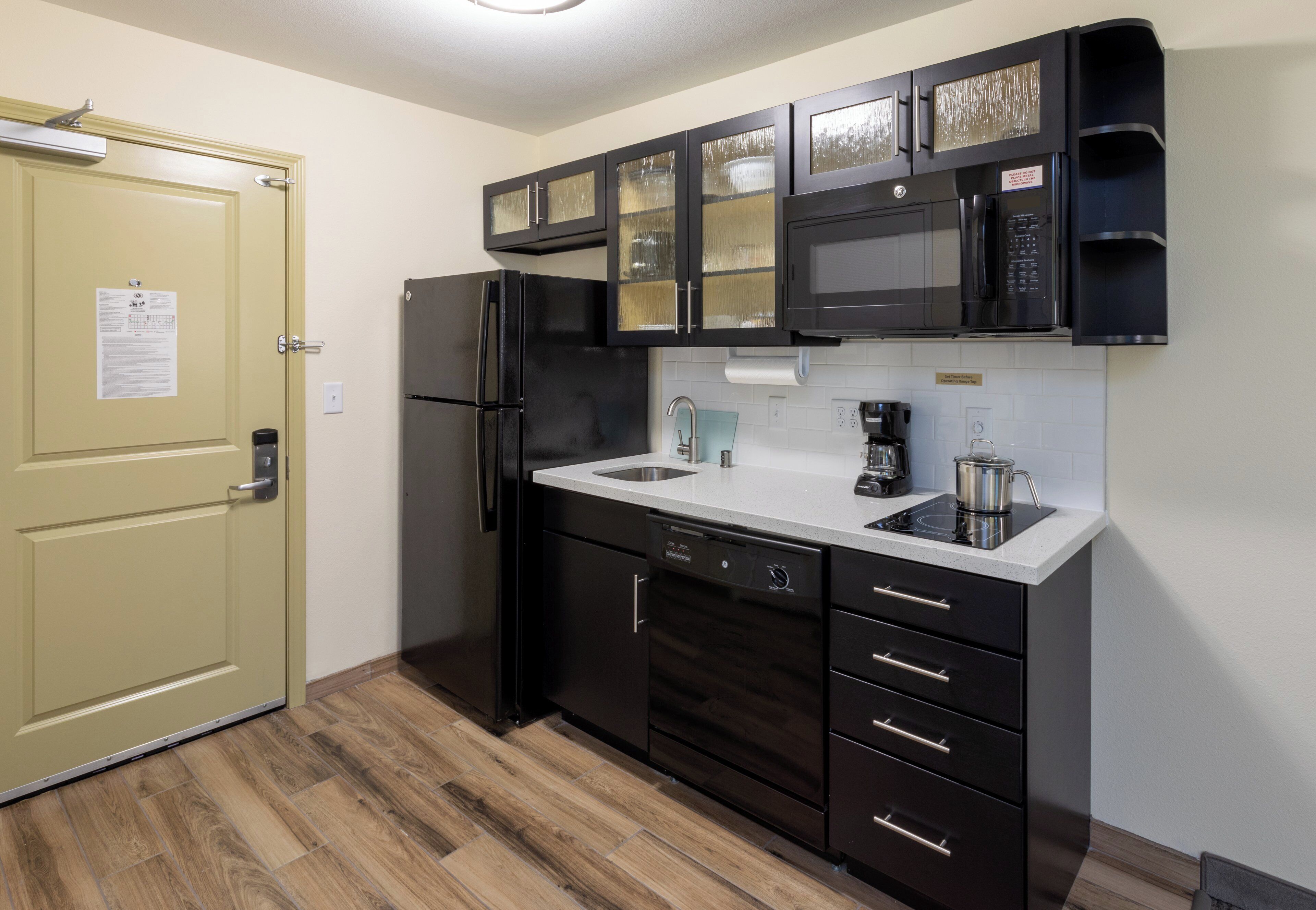 A compact kitchen with a refrigerator, microwave, and a coffee maker on the counter.