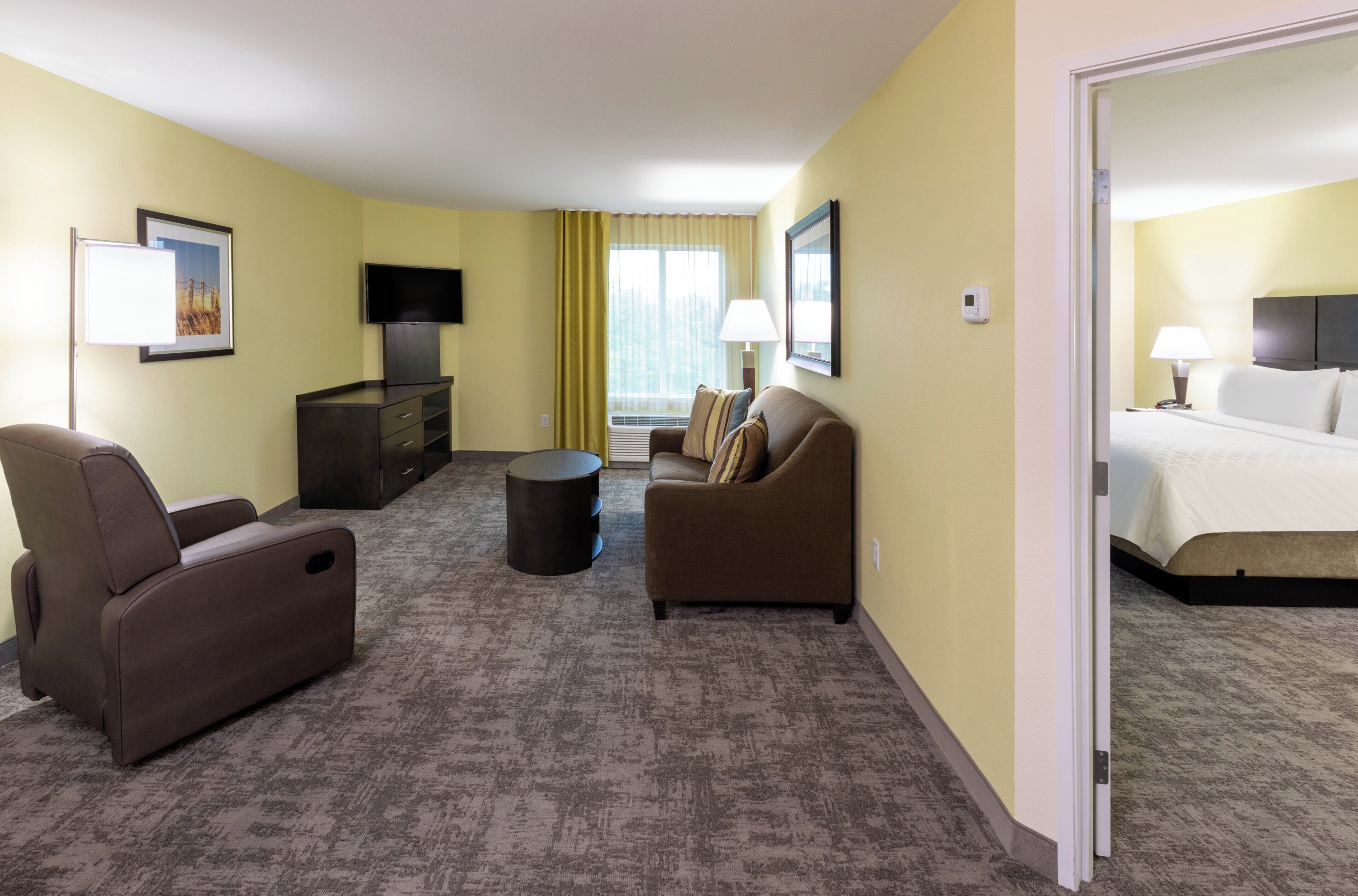 Ein Hotelzimmer mit Sofa, Ohrensessel, Fernseher und Bett.