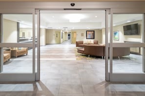 A hotel lobby with a reception desk, seating area, and a large window. - Candlewood Suites Rochester Mayo Clinic Area by IHG (Rochester)