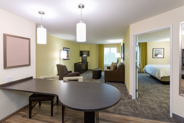 A hotel room with a large round table, two sofas, a TV, and a bed. - Candlewood Suites Rochester Mayo Clinic Area by IHG (Rochester)