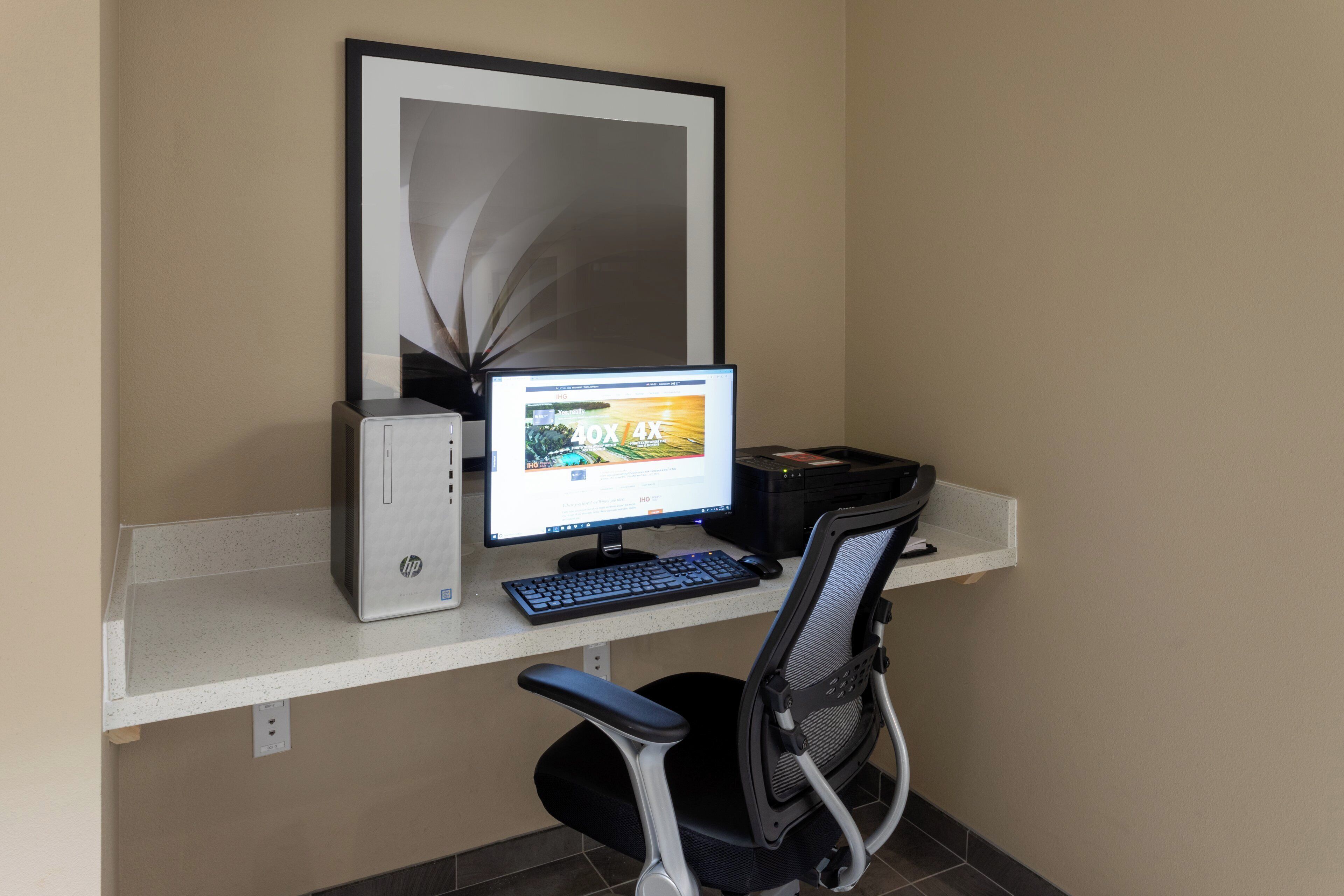 A computer desk with a desktop computer, keyboard, and chair.