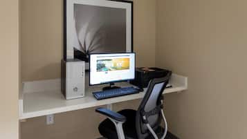 A computer desk with a desktop computer, keyboard, and chair.