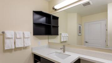 A bathroom with a double sink, a mirror, and a towel rack with multiple towels.
