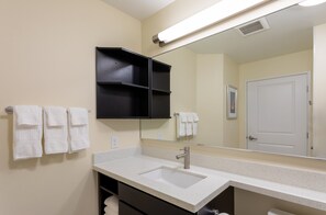 A bathroom with a double sink, a mirror, and a towel rack with multiple towels. - Candlewood Suites Rochester Mayo Clinic Area by IHG (Rochester)