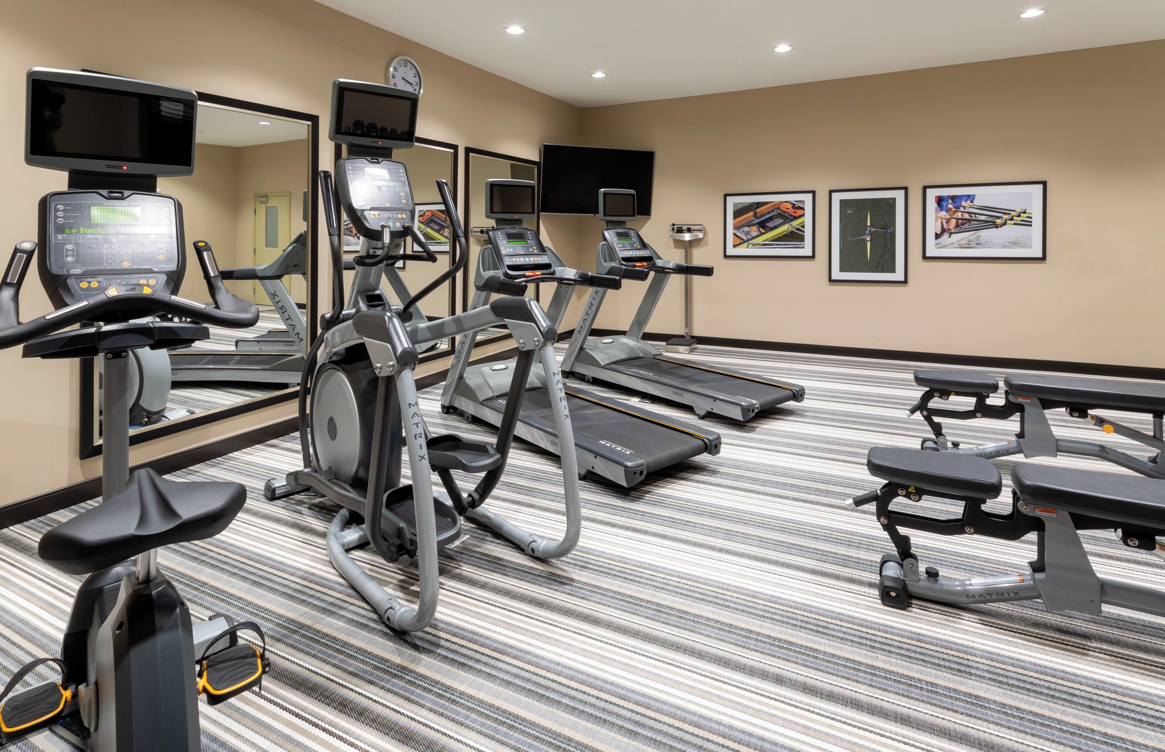 A hotel fitness center with treadmills, elliptical machines, and a mirrored wall.