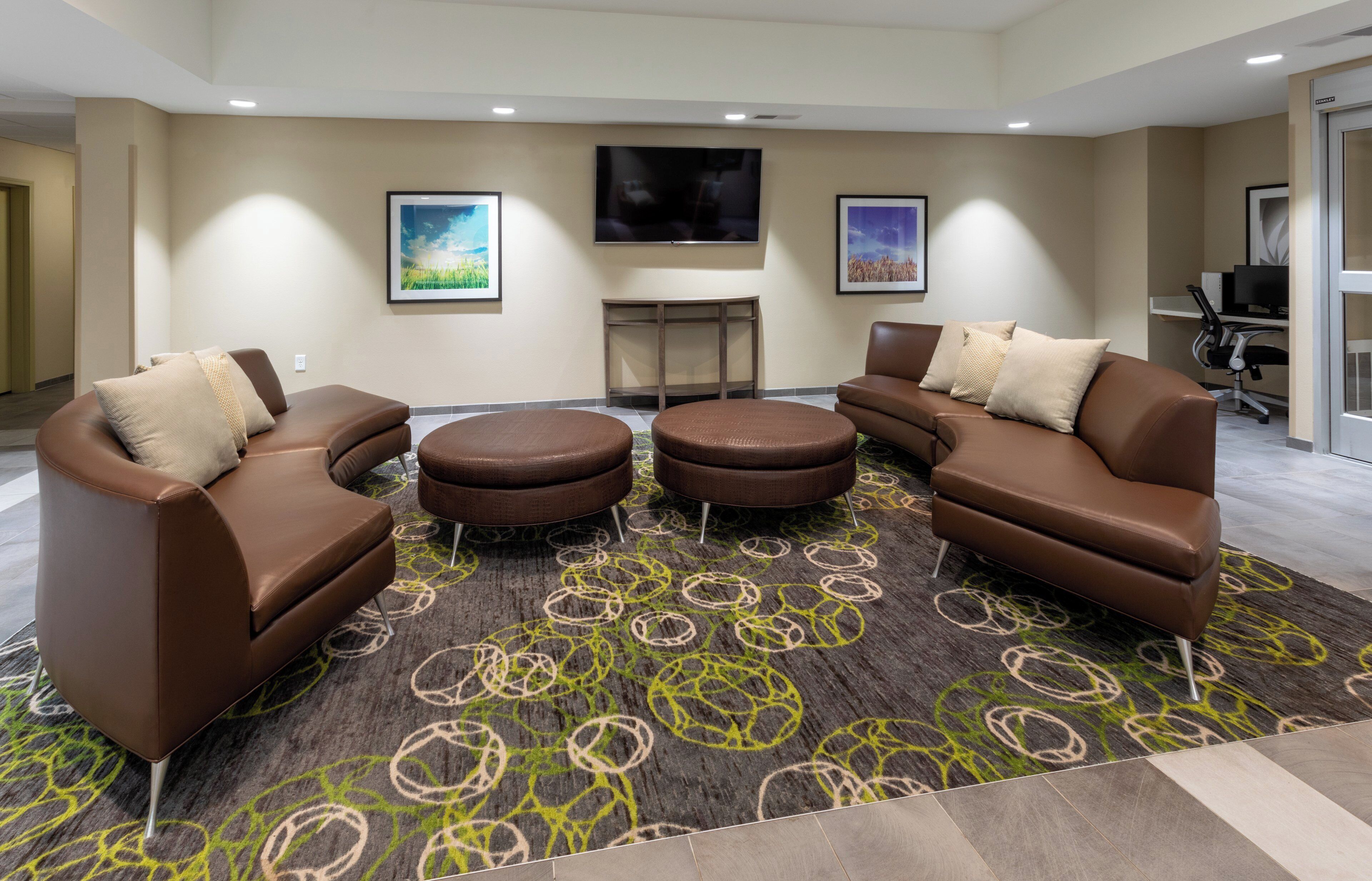 A modern lounge area with leather sofas, a coffee table, and a flat-screen TV mounted on the wall.