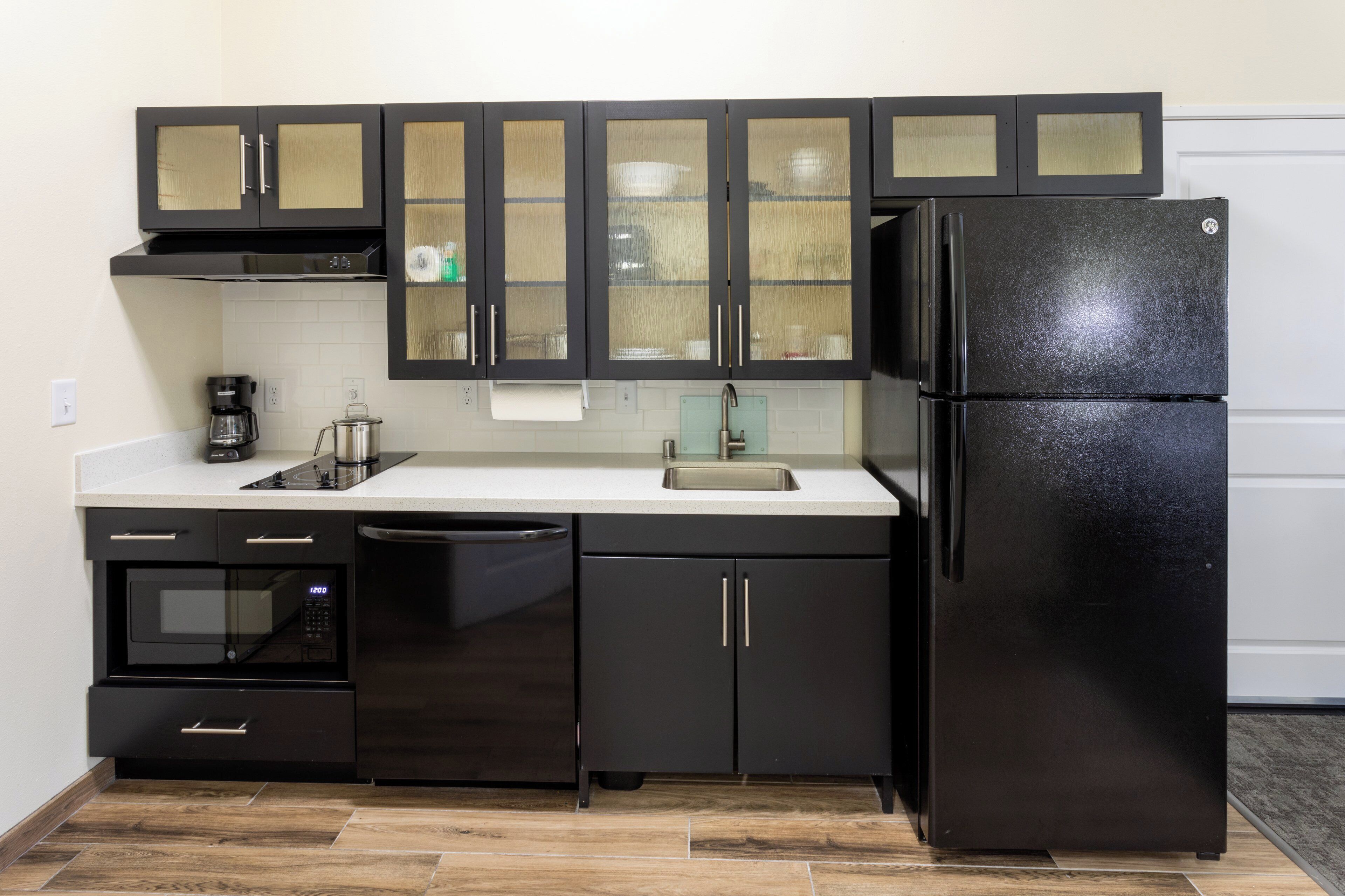 A compact kitchen with black cabinets, a stainless steel refrigerator, a coffee maker, and a microwave.