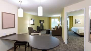 A hotel room with a dining area, a sofa, a TV, and a bed.